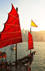 A red sail boat floating on the water.