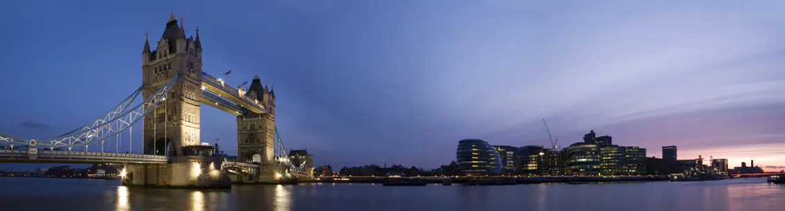 A city skyline with buildings and water at night.