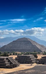 A pyramid shaped building in the middle of an open field.