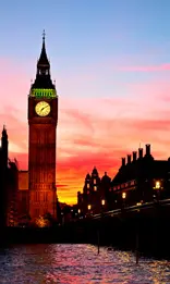 A clock tower in the middle of a city at night.