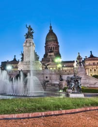 A fountain in front of a large building with many statues.