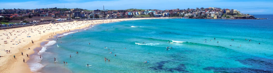 A beach with people swimming and surfing in the water.