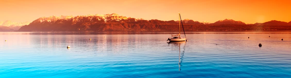 A sailboat is in the water at sunset.