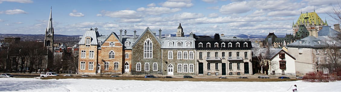 A row of old stone buildings with snow on the ground.