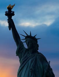 A statue of liberty with the sun setting behind it.