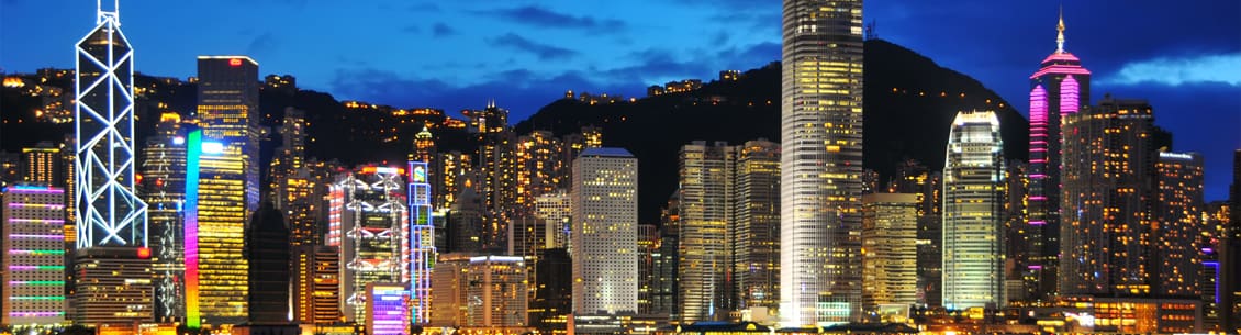 A city skyline with buildings lit up at night.