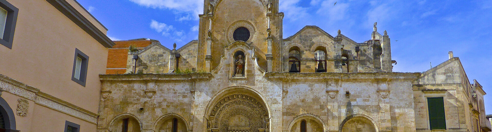 Ornate stone church facade, sunny day.